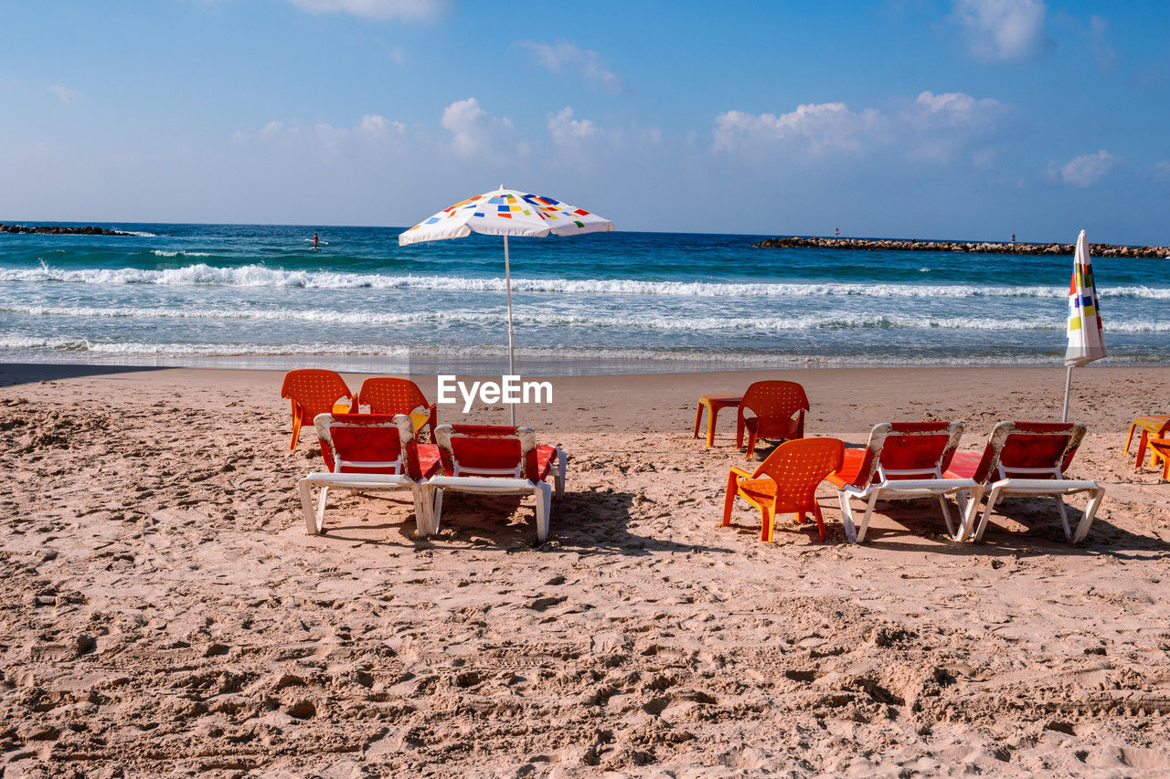 lounge chairs on beach against sky