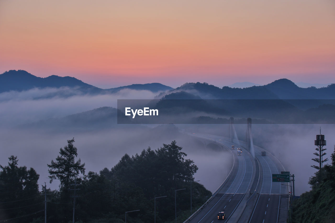 High angle view of road amidst trees against orange sky