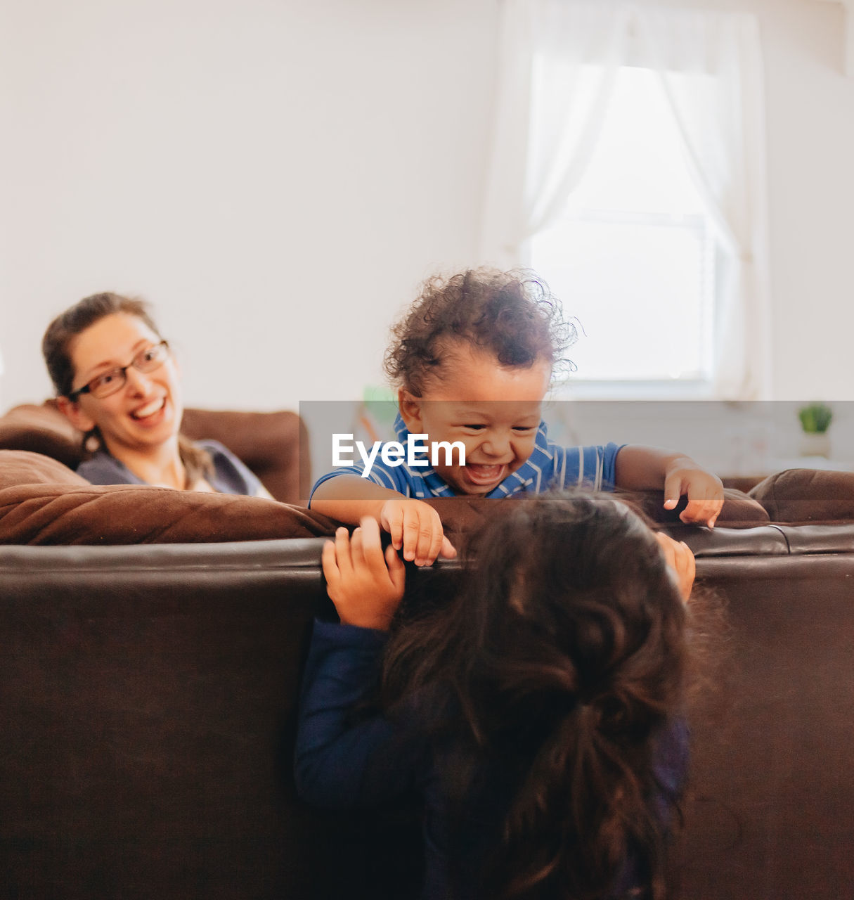 Smiling mother with kids sitting on sofa at home