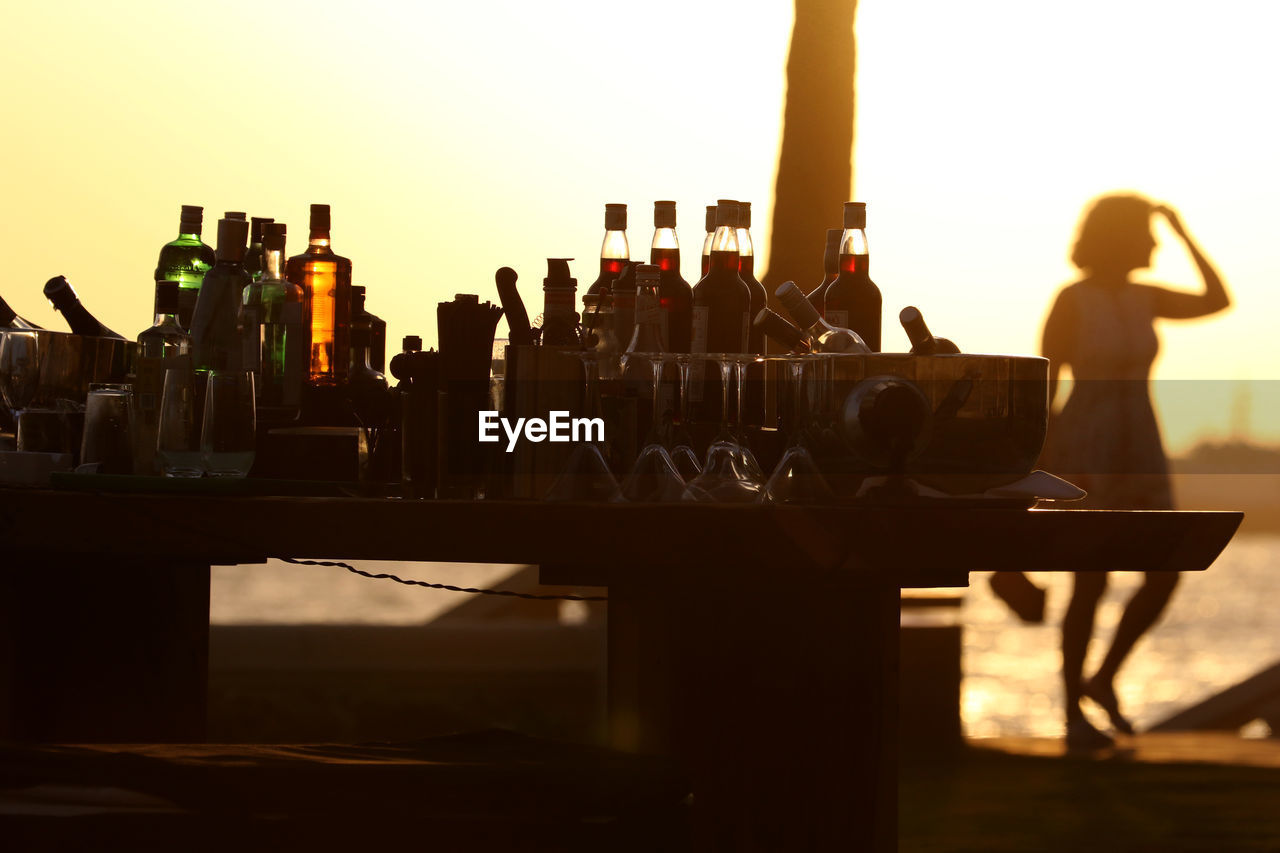 Silhouette drinks on table against clear sky during sunset