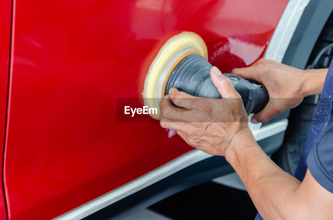 Cropped hands of mechanic polishing car in garage