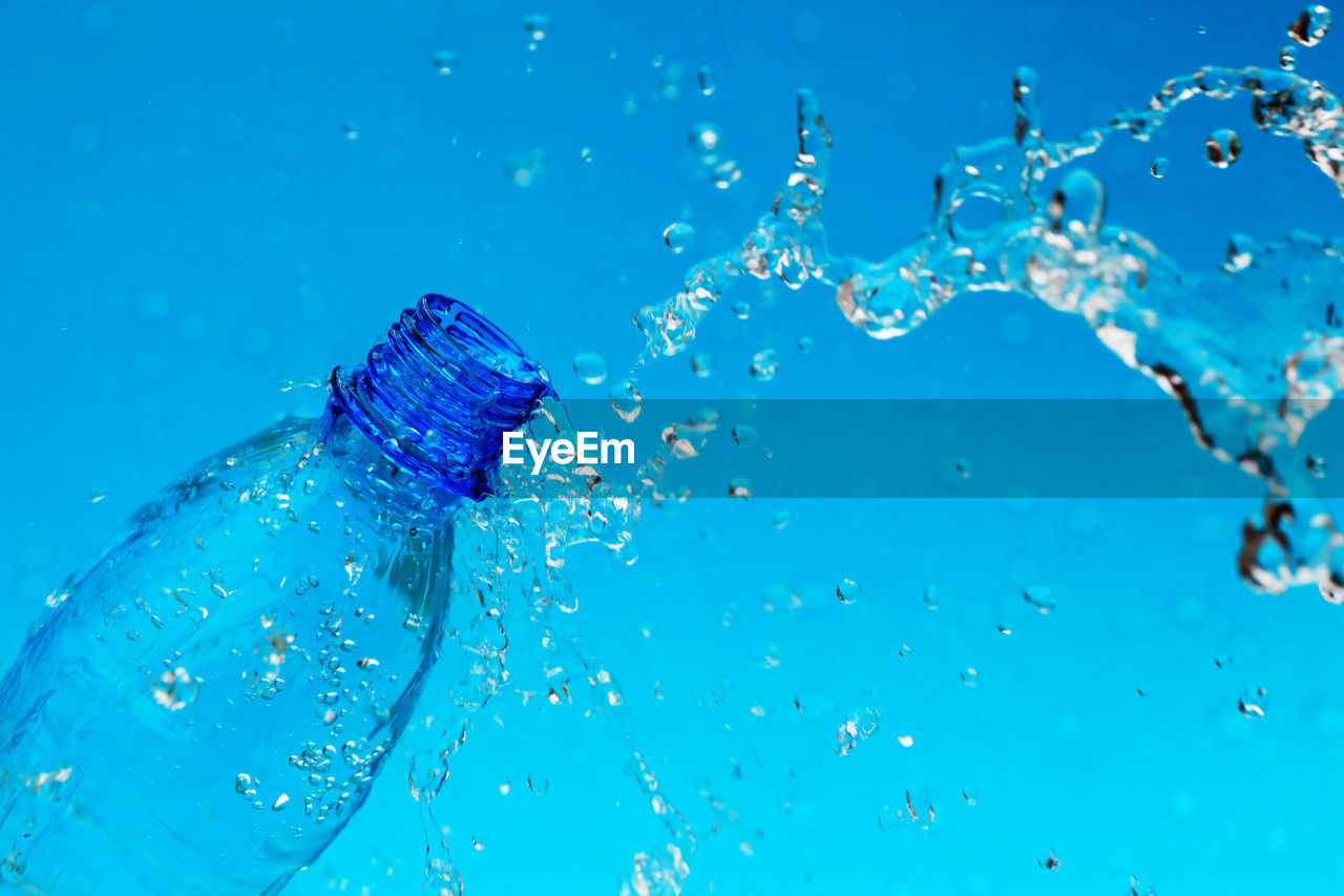 CLOSE-UP OF WATER SPLASHING AGAINST BLUE SKY