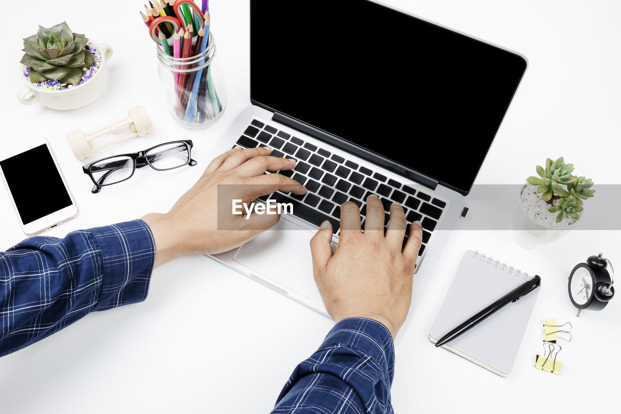 Cropped hands of man using laptop on table