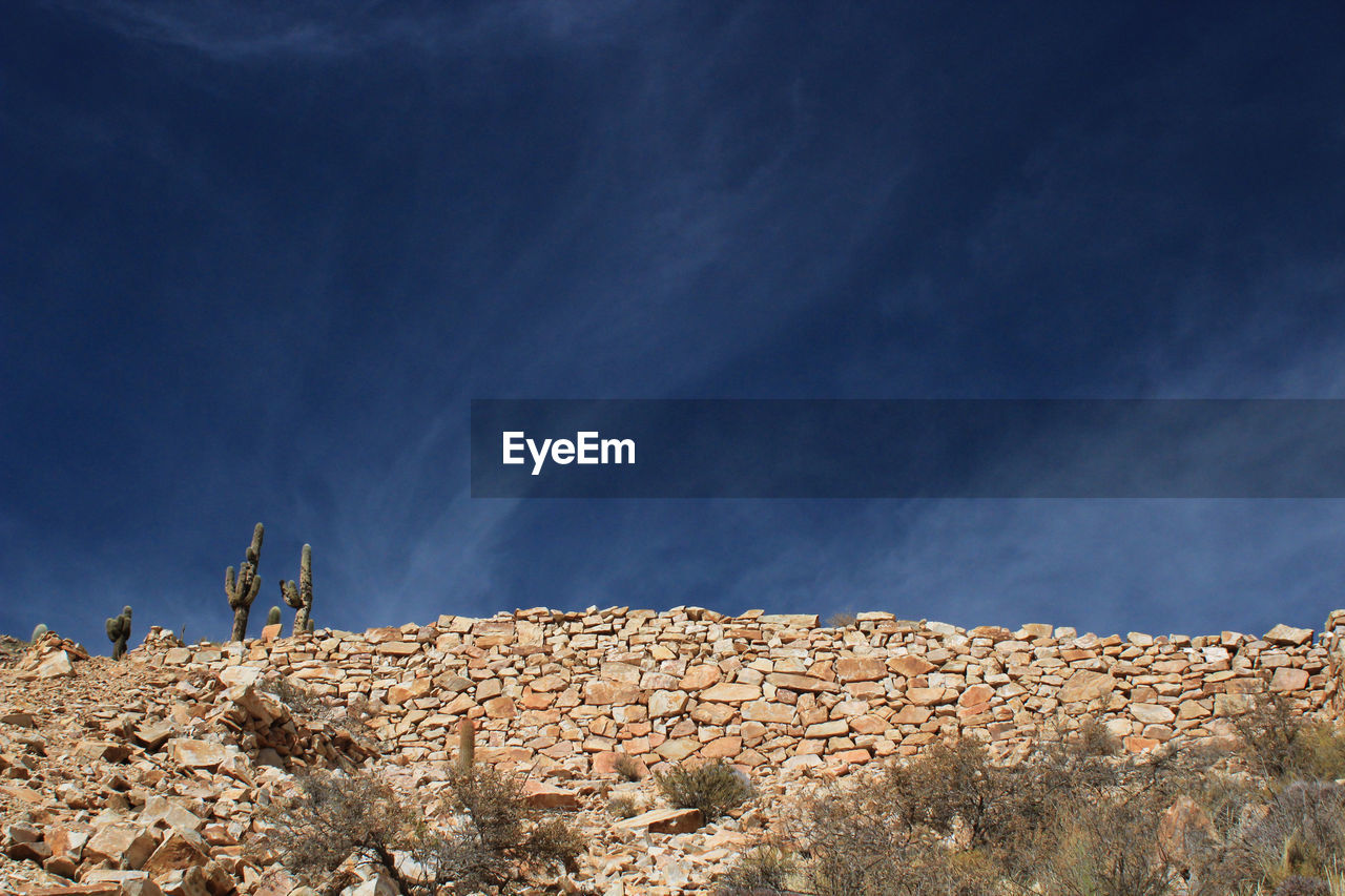 LOW ANGLE VIEW OF STONE WALL AGAINST SKY