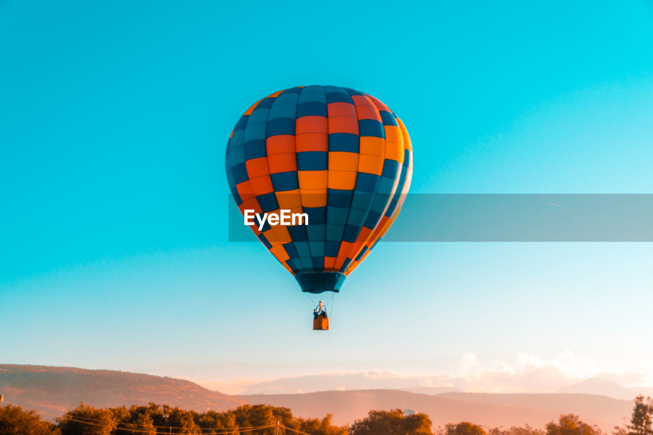 Low angle view of hot air balloon flying in mid-air against clear blue sky