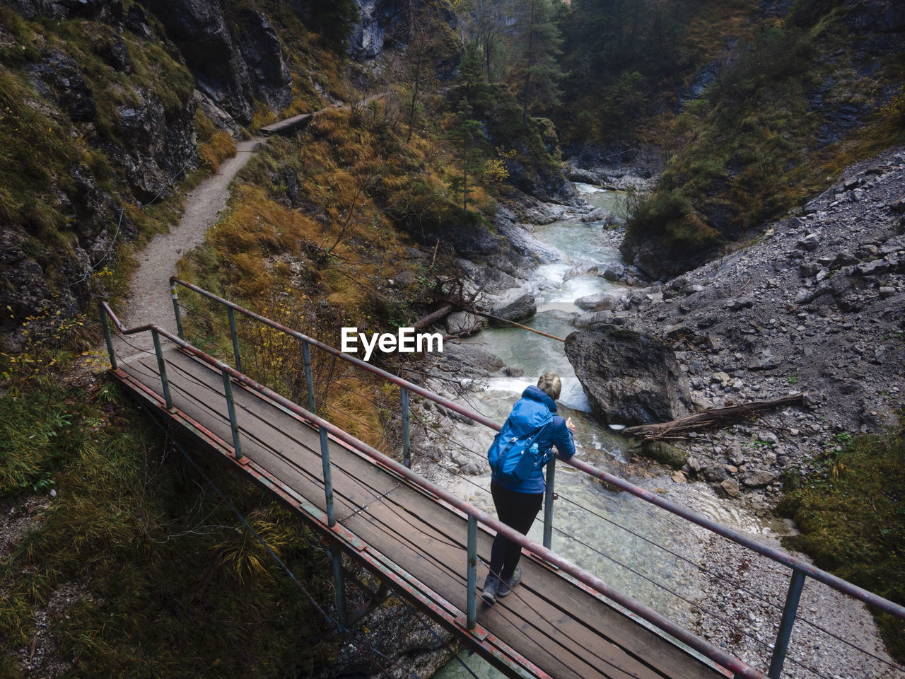 Austria, lower austria, annaberg, drone view of female hiker standing on bridge stretching over otscherbach river