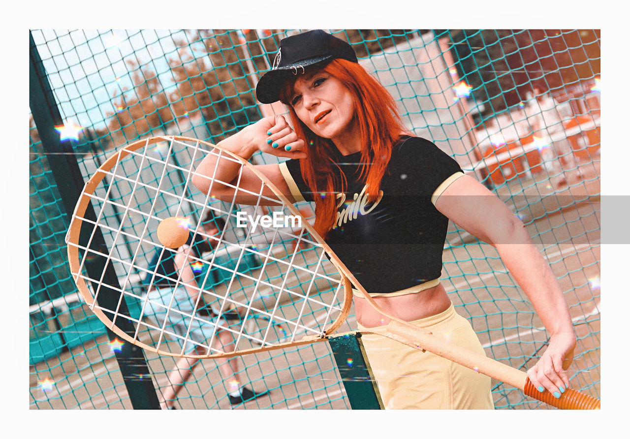 Portrait of mature woman holding tennis racket standing outdoors