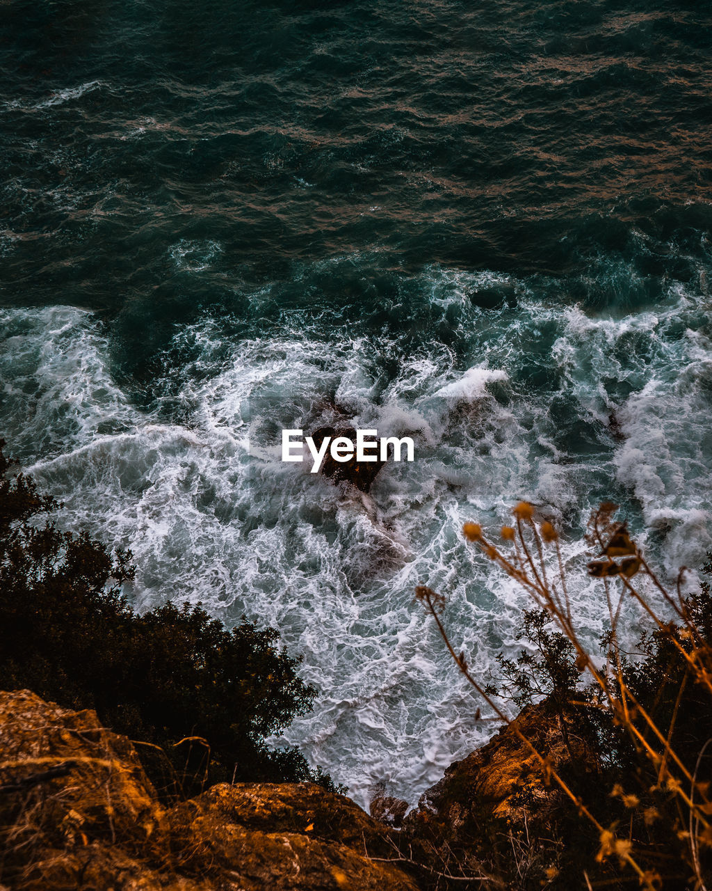 HIGH ANGLE VIEW OF WAVES BREAKING ON ROCKS