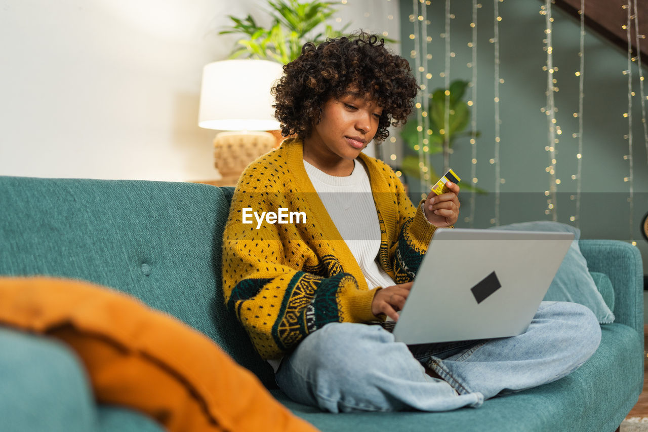 woman using laptop while sitting on sofa at home