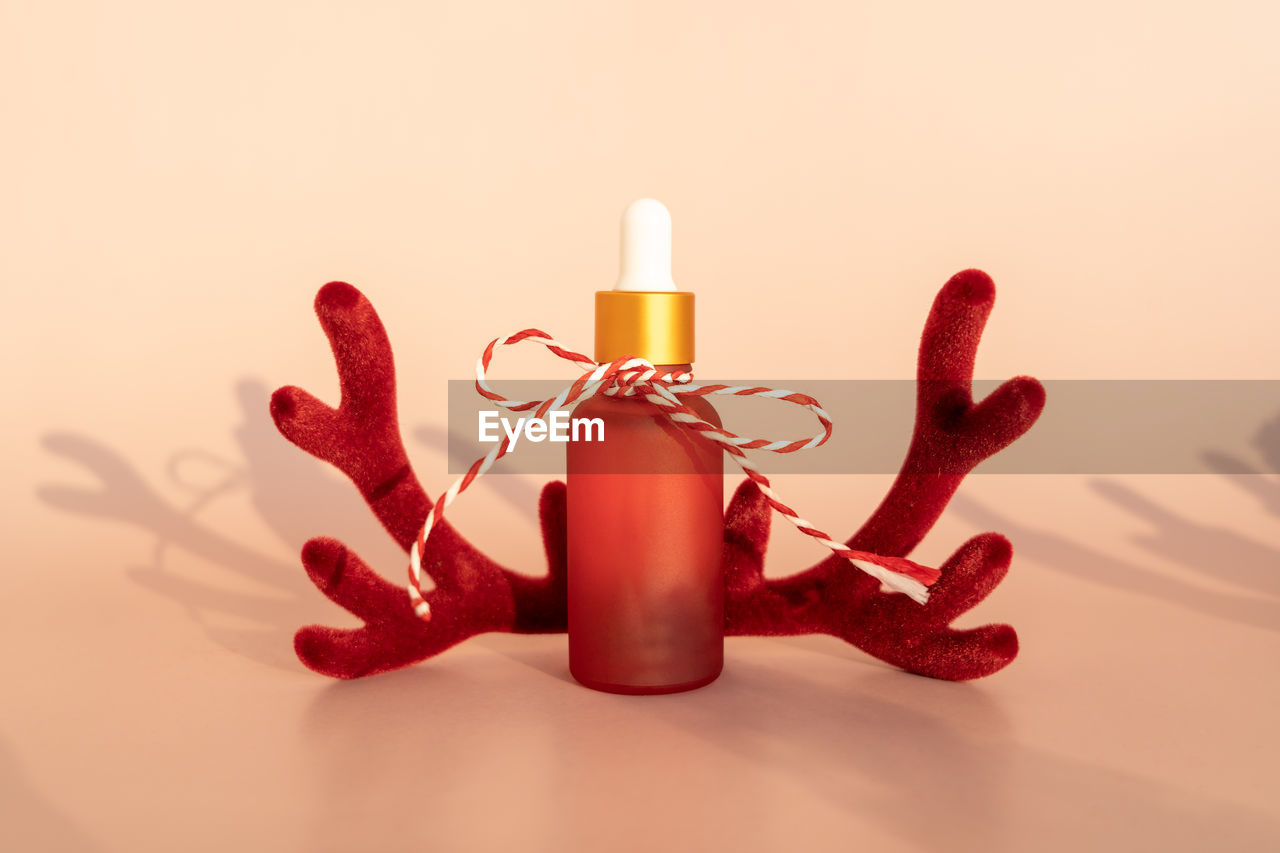 A dropper bottle of the natural essential oil or serum standing on a pink background as a present 