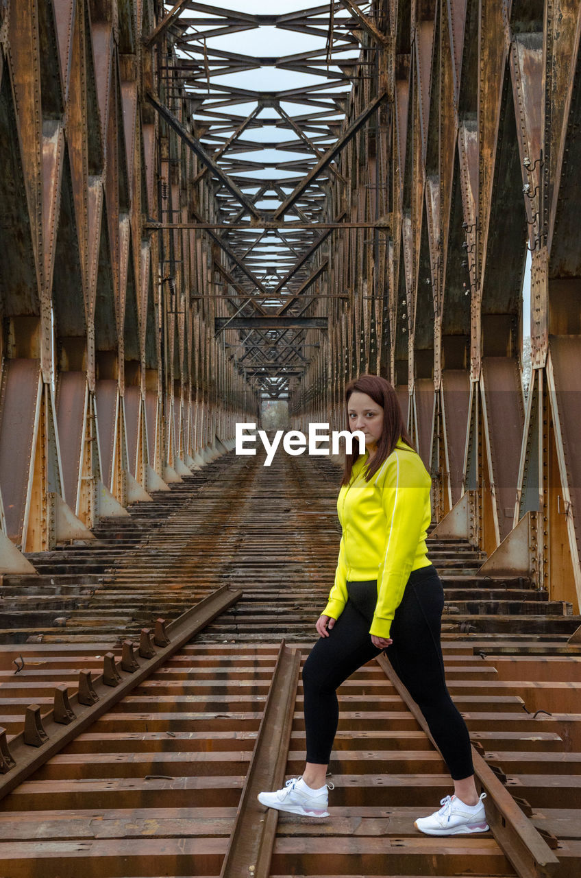 Portrait of young woman exercises on railway