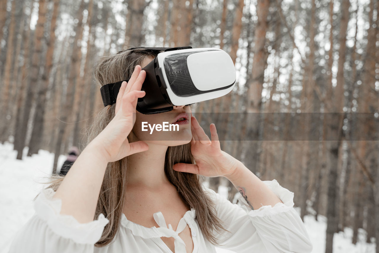 Woman wearing virtual reality simulator against trees outdoors