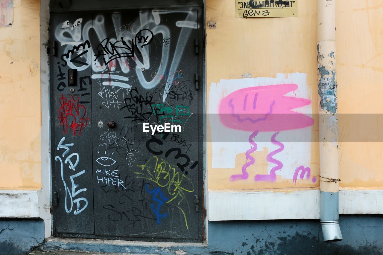 GRAFFITI ON WALL OF MULTI COLORED DOOR