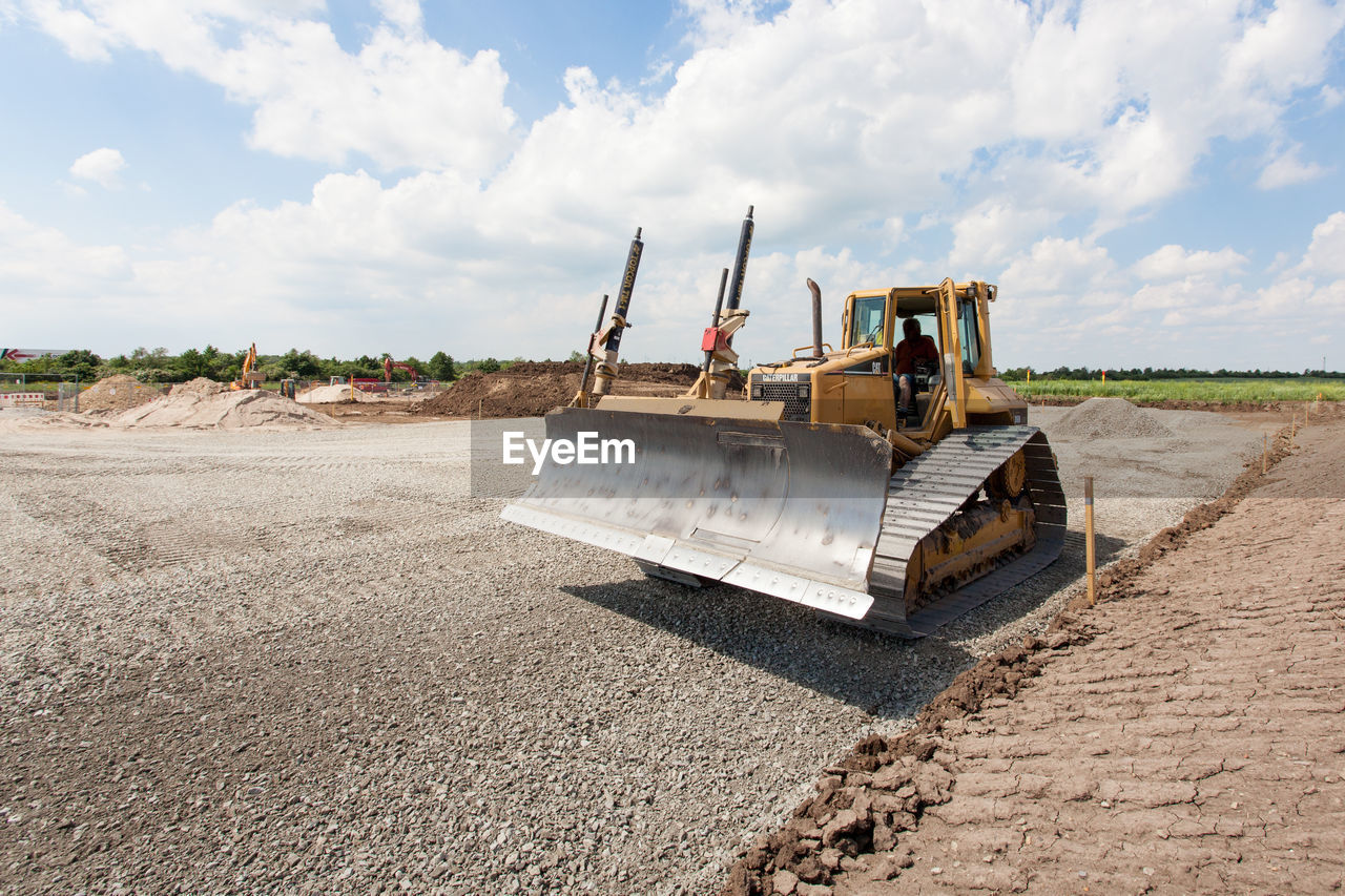 Man driving bulldozer at construction site against sky