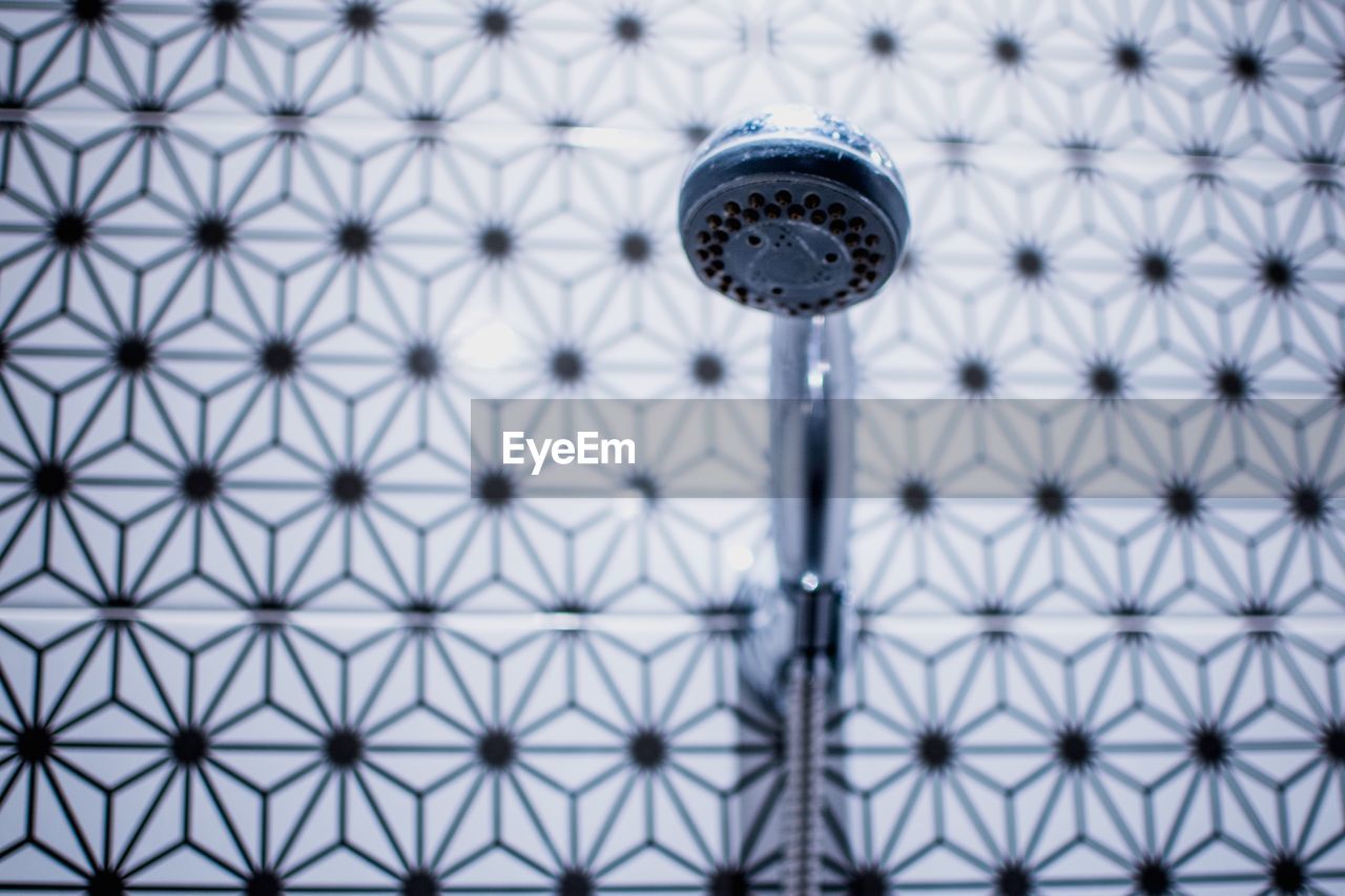 Close-up of shower head against wall in bathroom