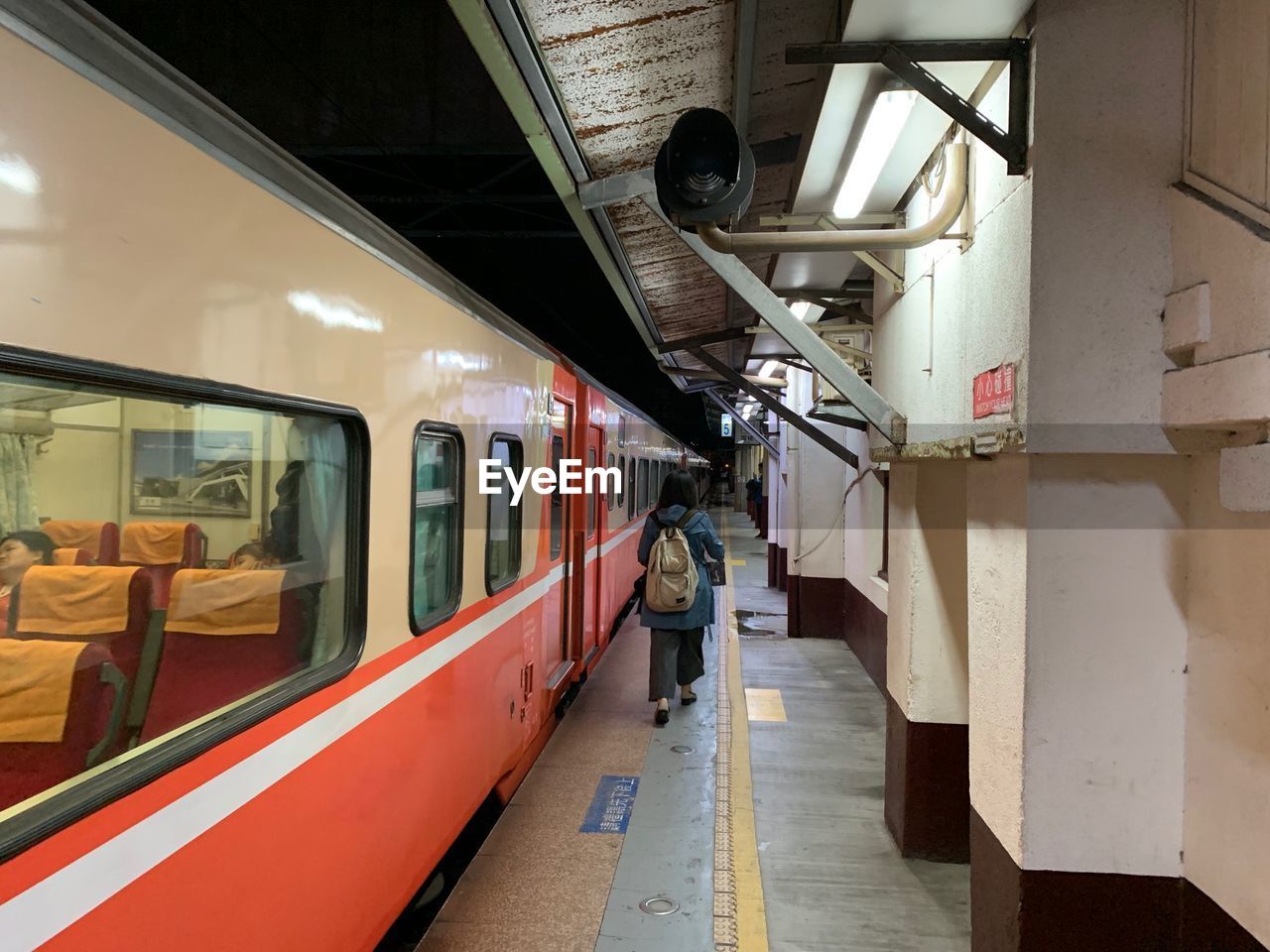 REAR VIEW OF PEOPLE STANDING ON RAILROAD STATION PLATFORM