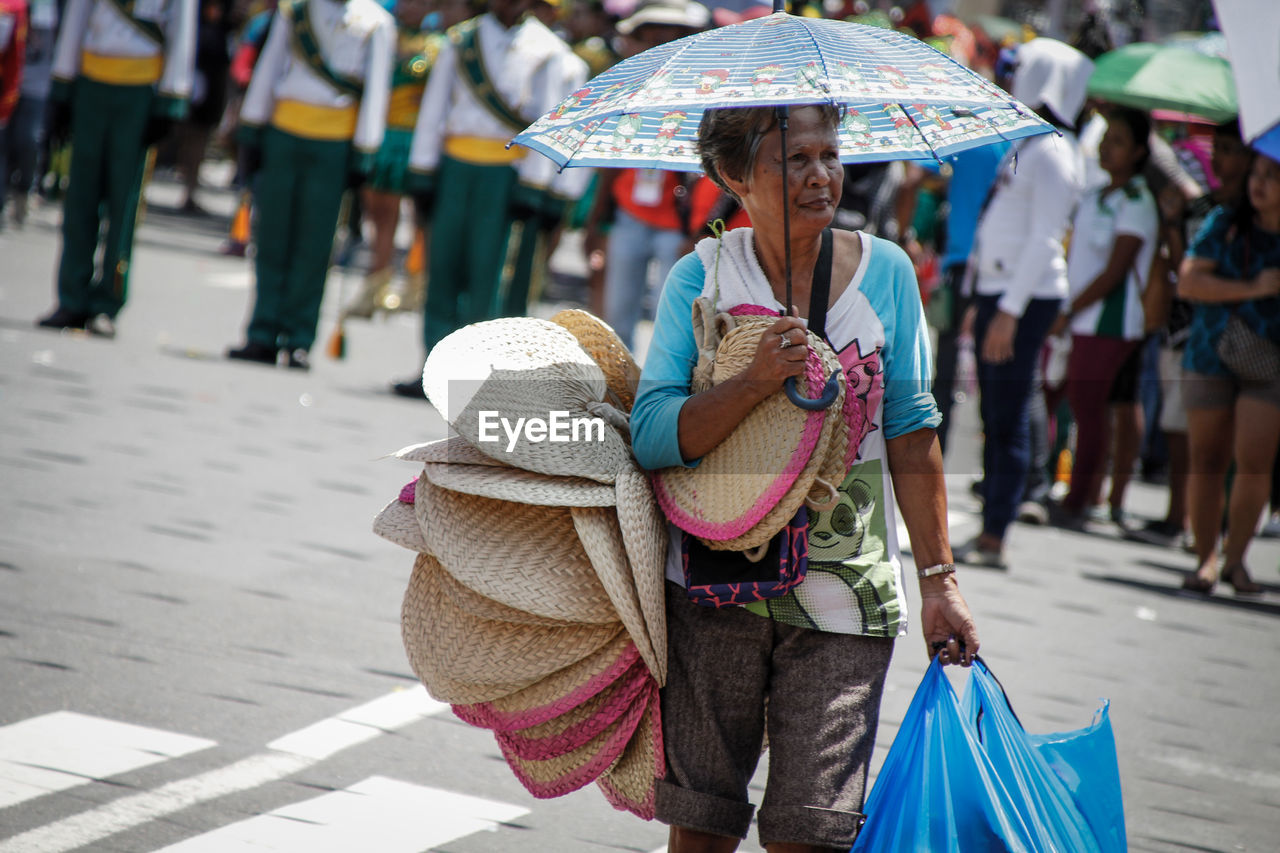 Senior woman with umbrella selling bags in market