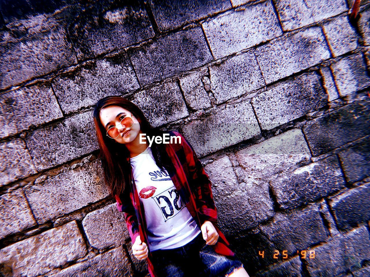 HIGH ANGLE PORTRAIT OF A SMILING WOMAN STANDING AGAINST WALL