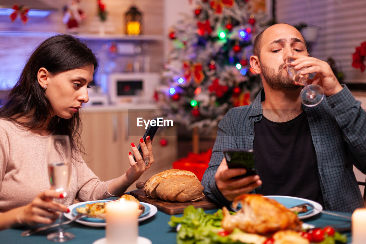 Young man and woman having food on christmas tree