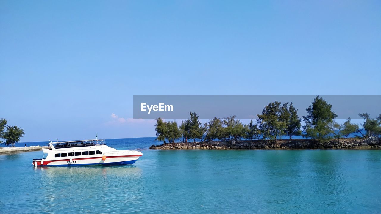 BOAT SAILING ON SEA AGAINST CLEAR BLUE SKY