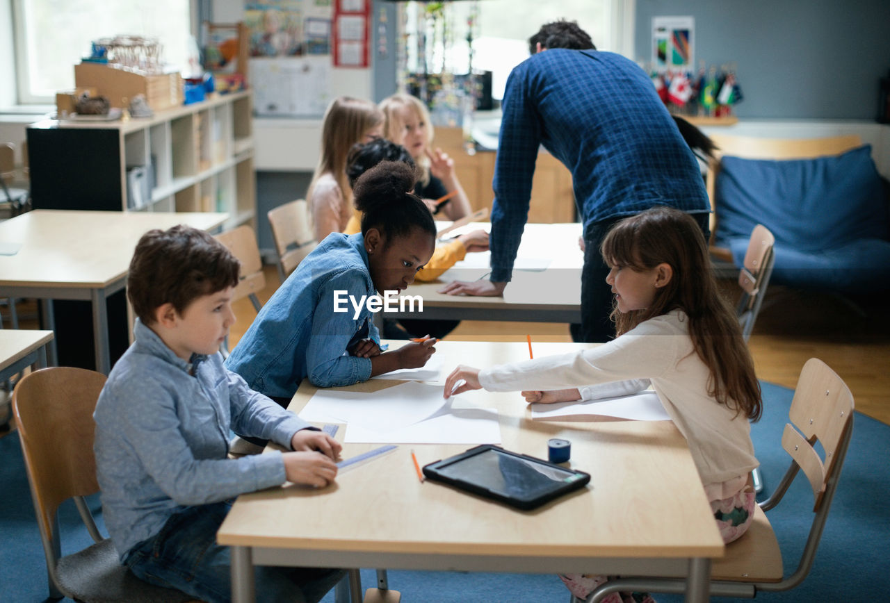 Teacher explaining children sitting in classroom at school