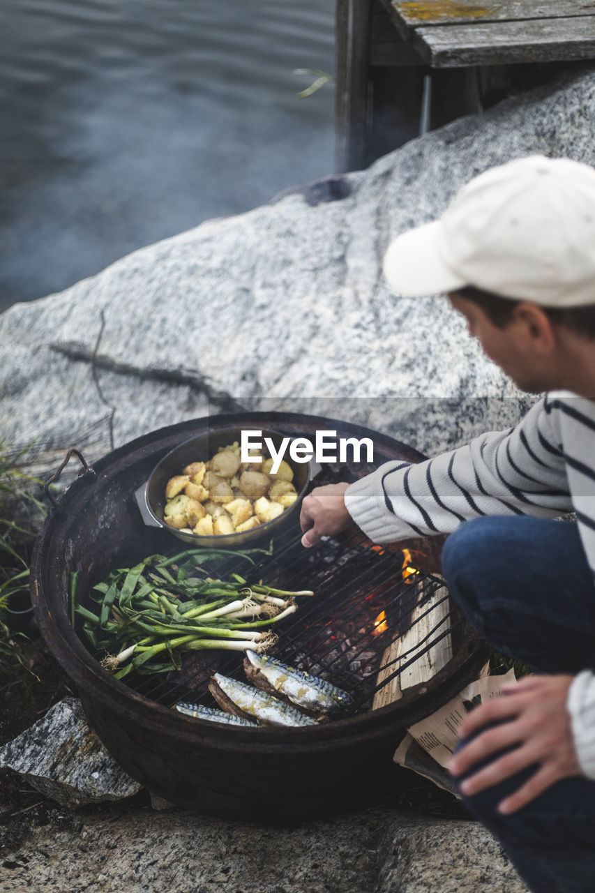 Mid adult man preparing food on barbecue grill at island