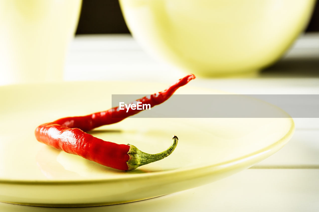 Red hot pepper on green dish over white wood. horizontal image.