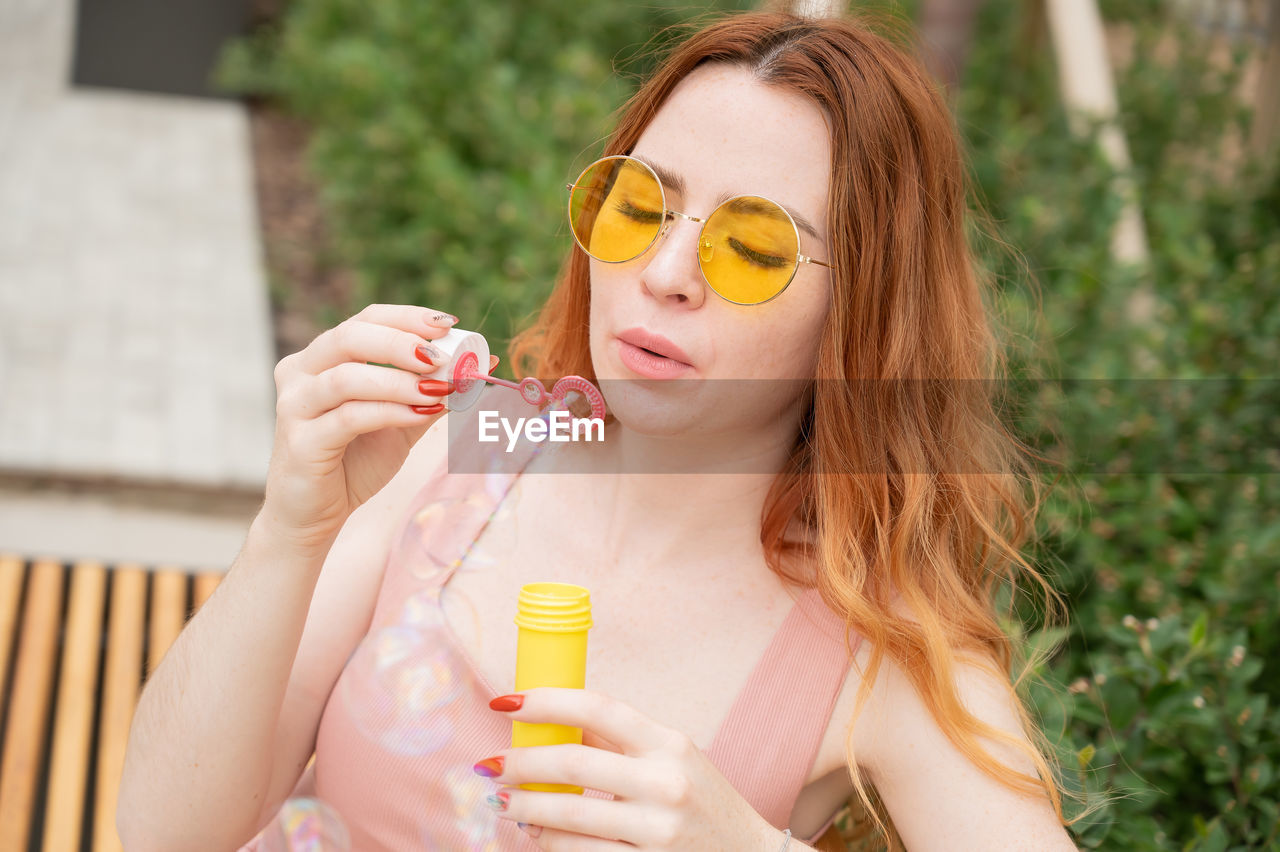 portrait of young woman wearing sunglasses while sitting outdoors