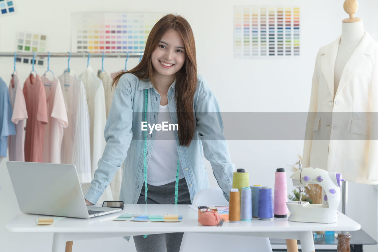A young woman tailors in a designer's workspace with design equipment.