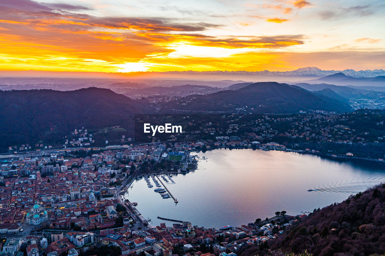 The city of como and the lake, photographed from brunate, at dusk, and mountains in the background.