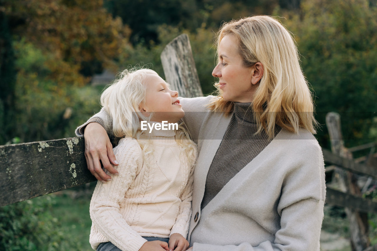 Mom with her little daughter on a walk outside on an autumn day.