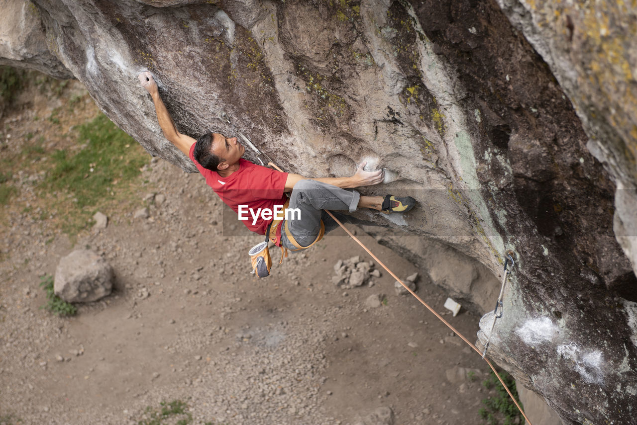 One man wearing red hold himself while rock climbing in jilotepec