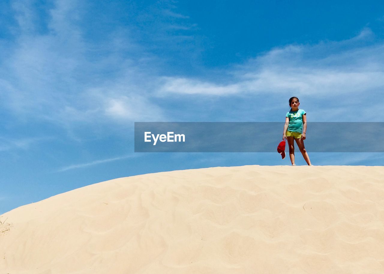Girl standing at desert against sky