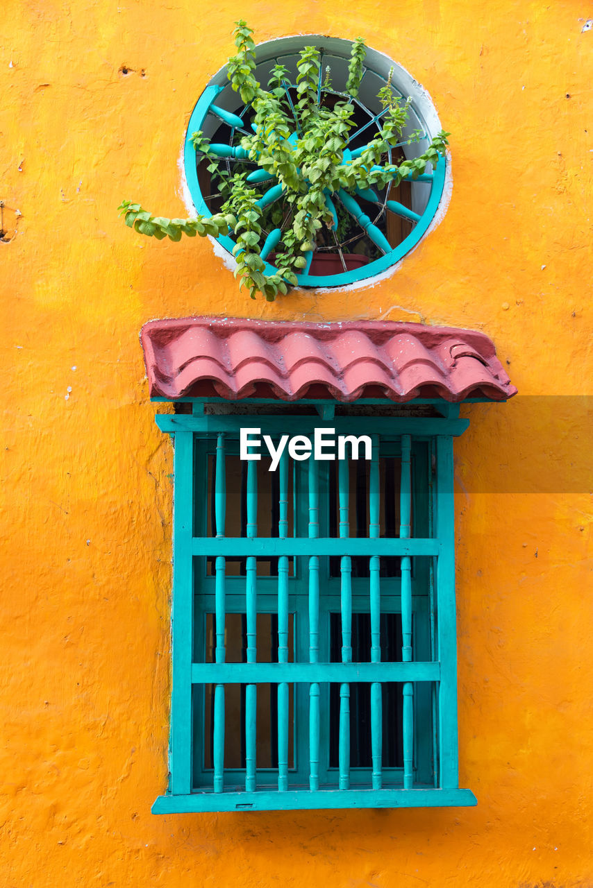 Turquoise window amidst yellow wall