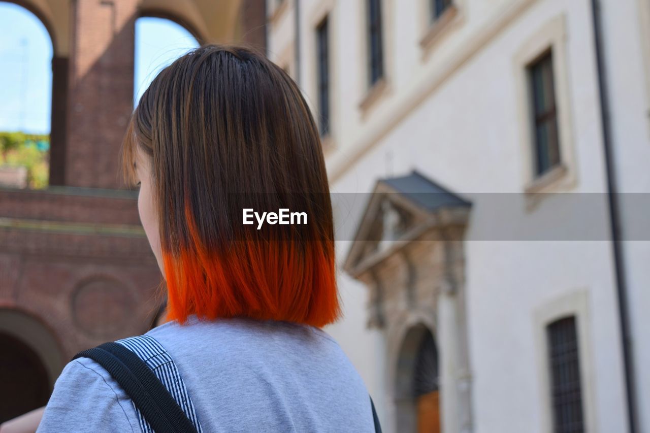 Woman with dyed hair standing against building