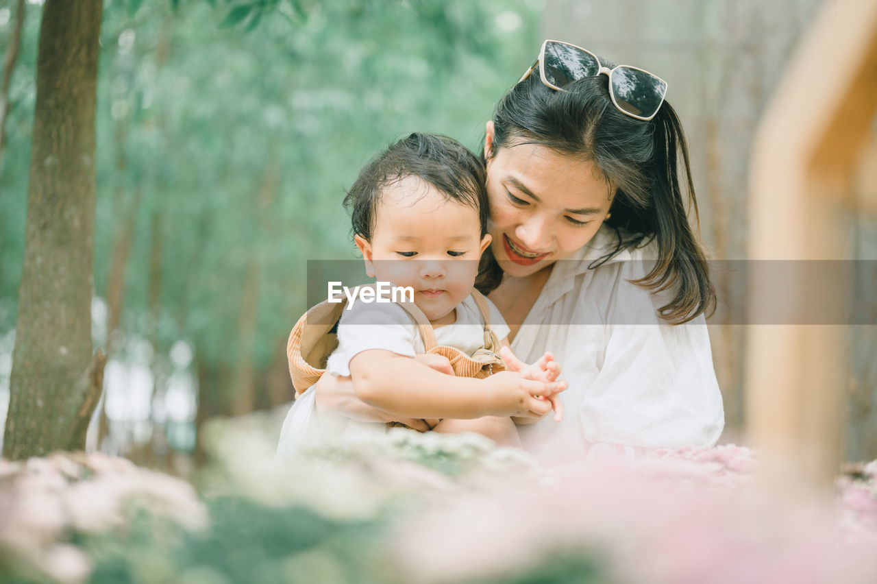 Mother and son standing by flowering plants