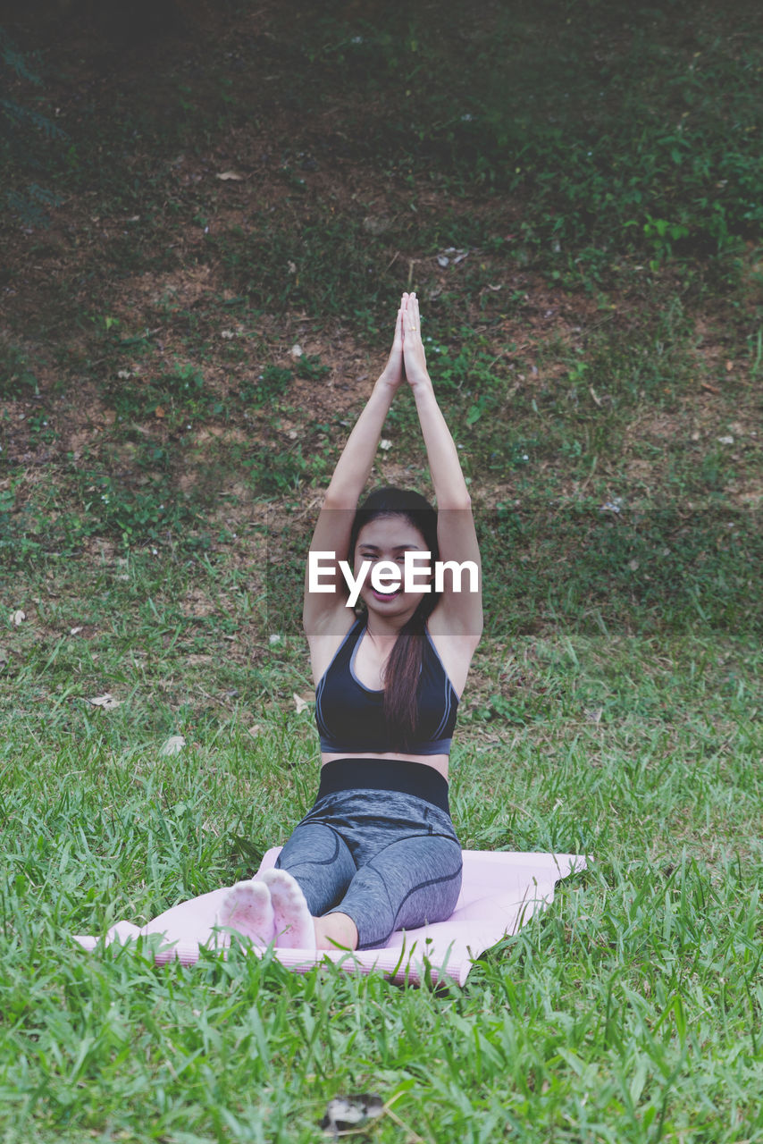 Woman practicing yoga while sitting on grass outdoors