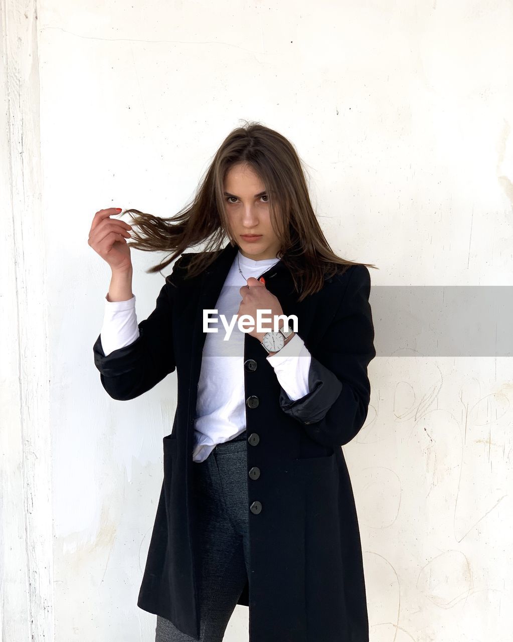 Portrait of young woman standing against wall