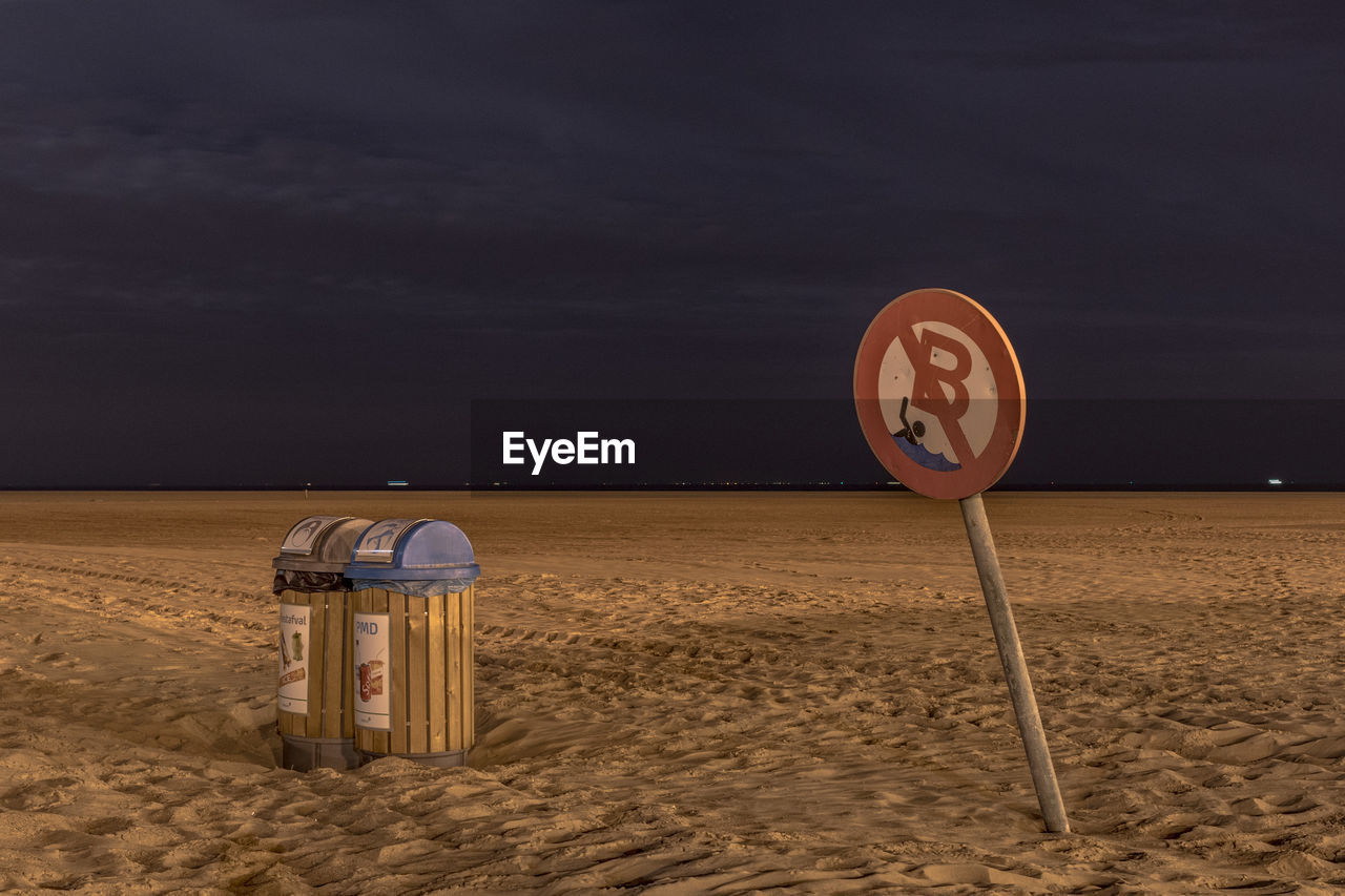 Information sign on beach against sky at night