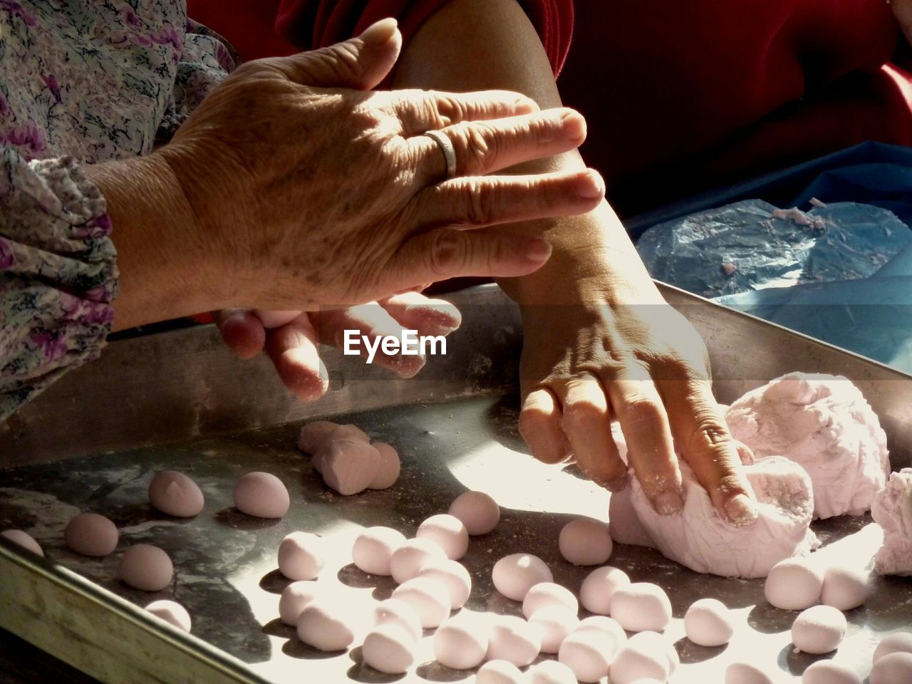 Midsection of women rolling rice cakes