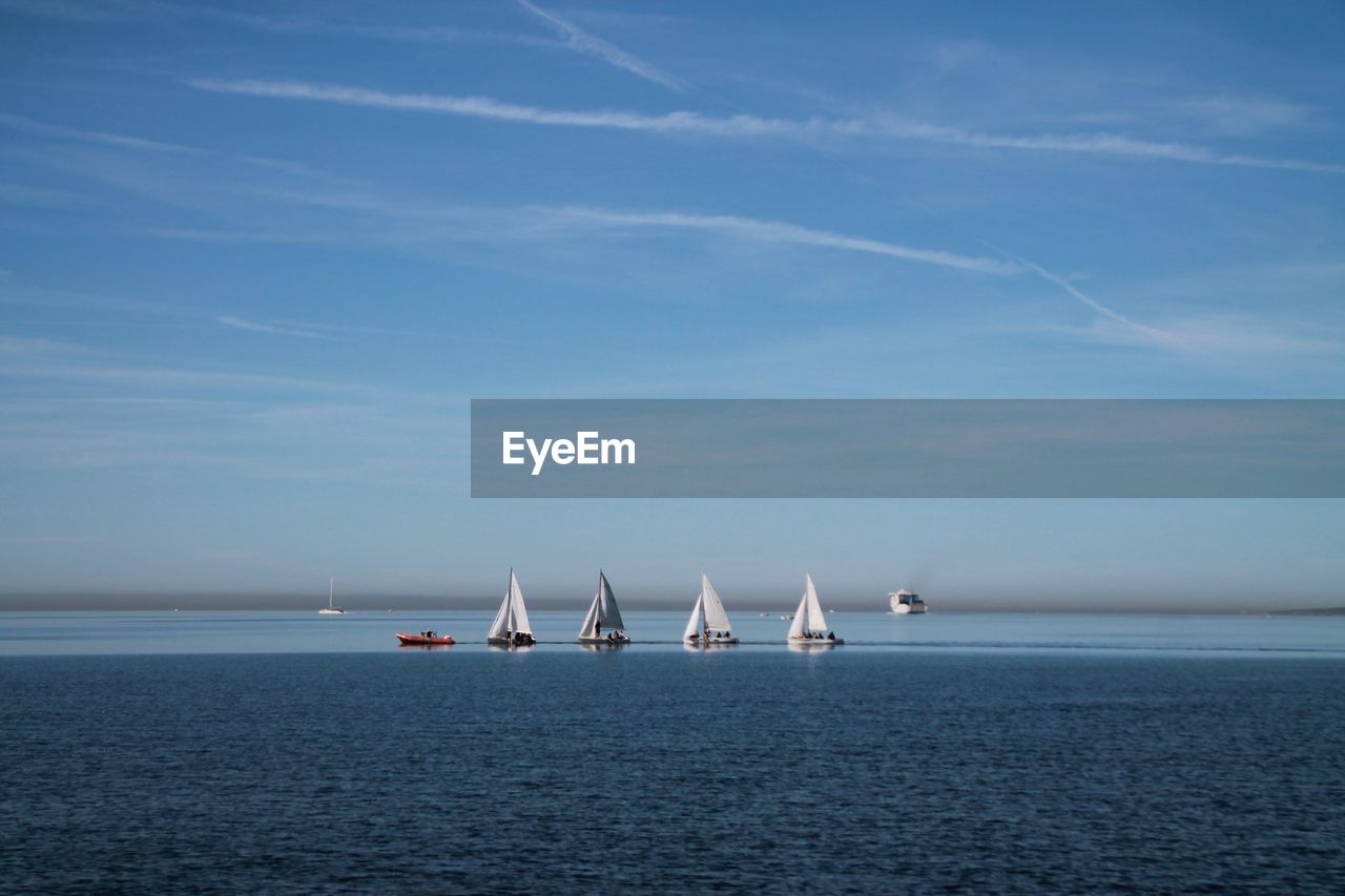 Sailboats sailing in sea against blue sky