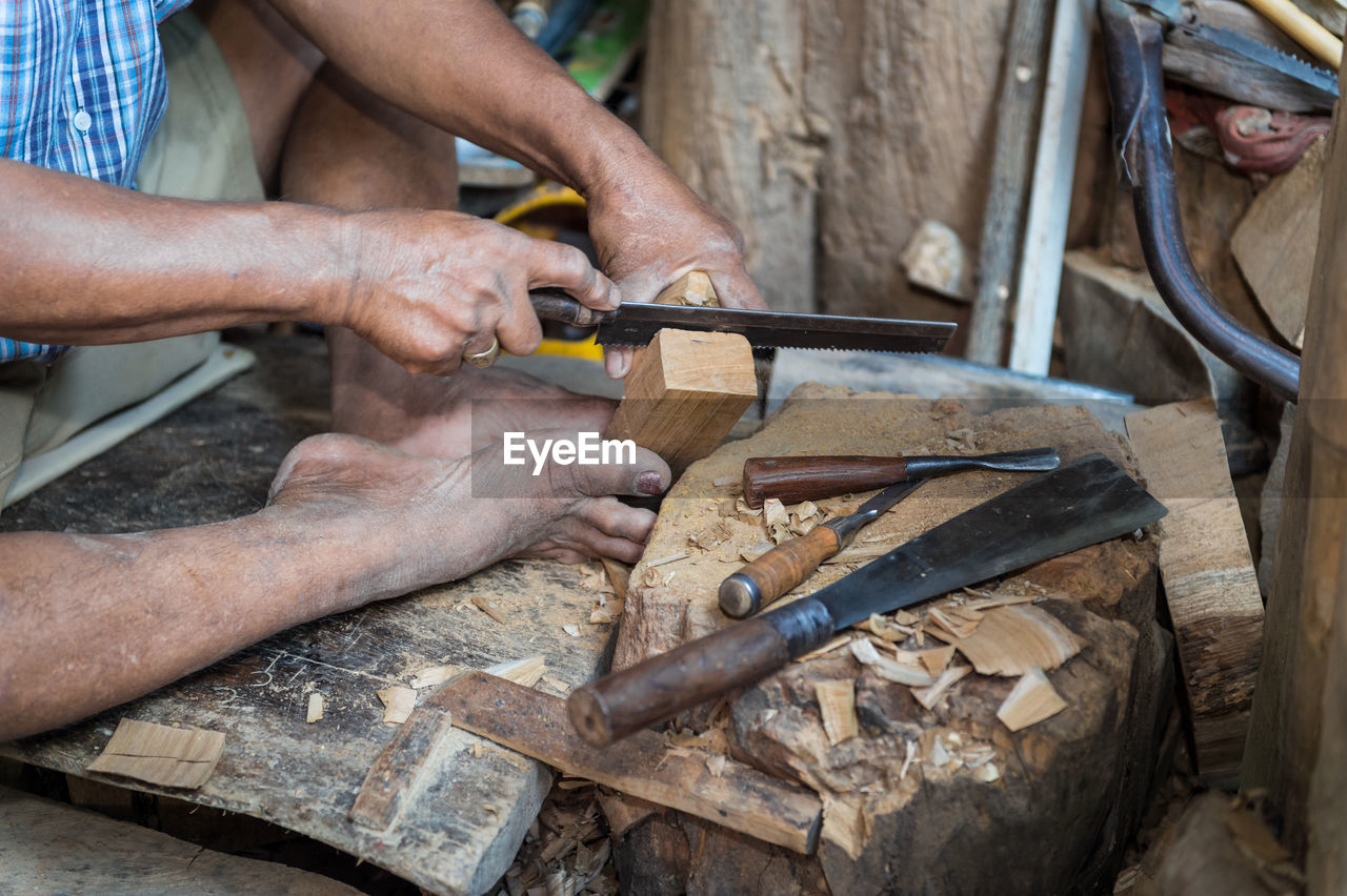 Midsection of man cutting wood