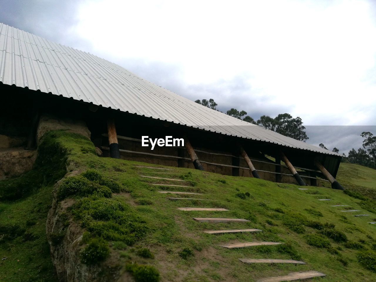 HOUSE ON FIELD BY HOUSES AGAINST SKY