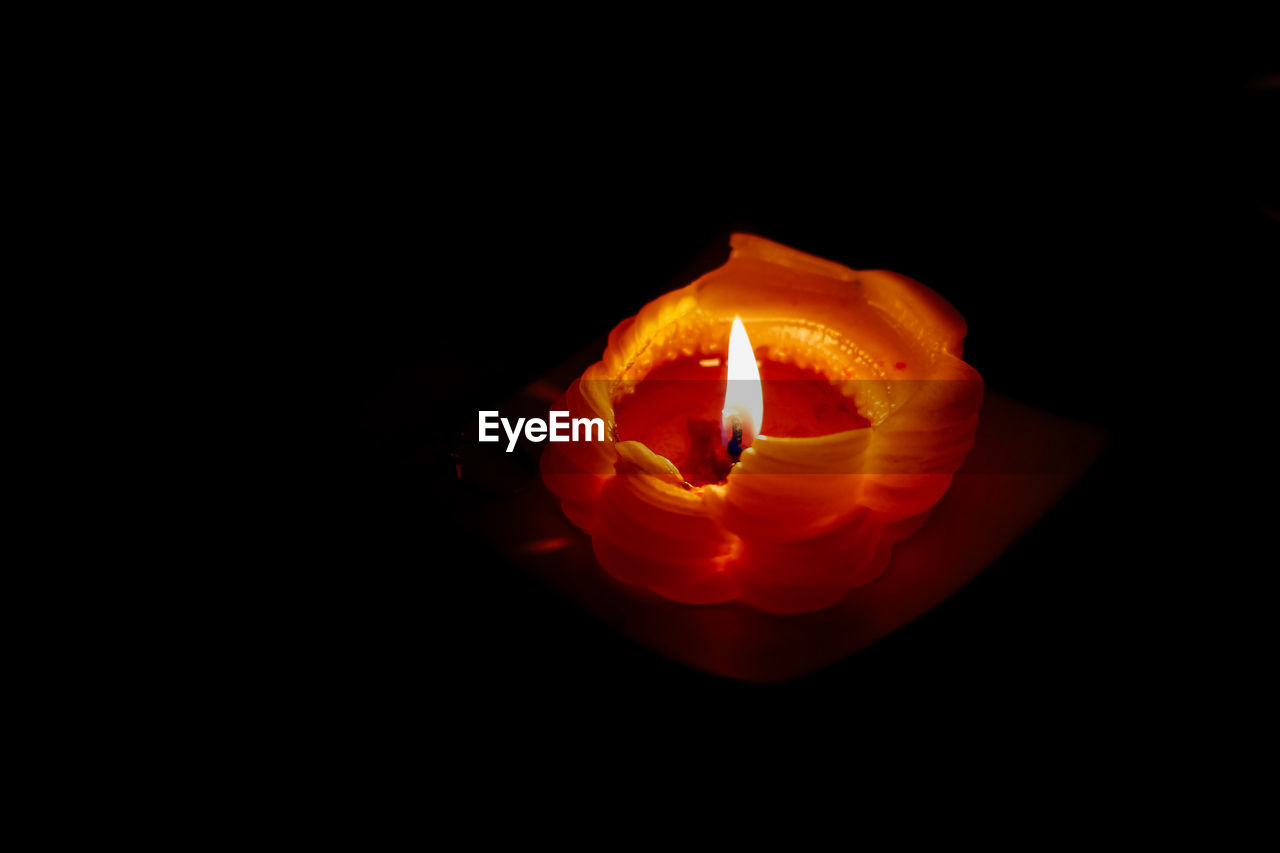 Close-up of lit candle against black background