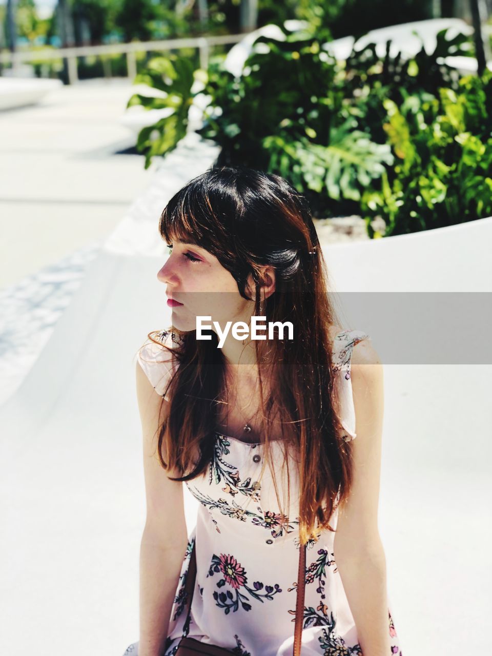 Young woman looking away while sitting outdoors