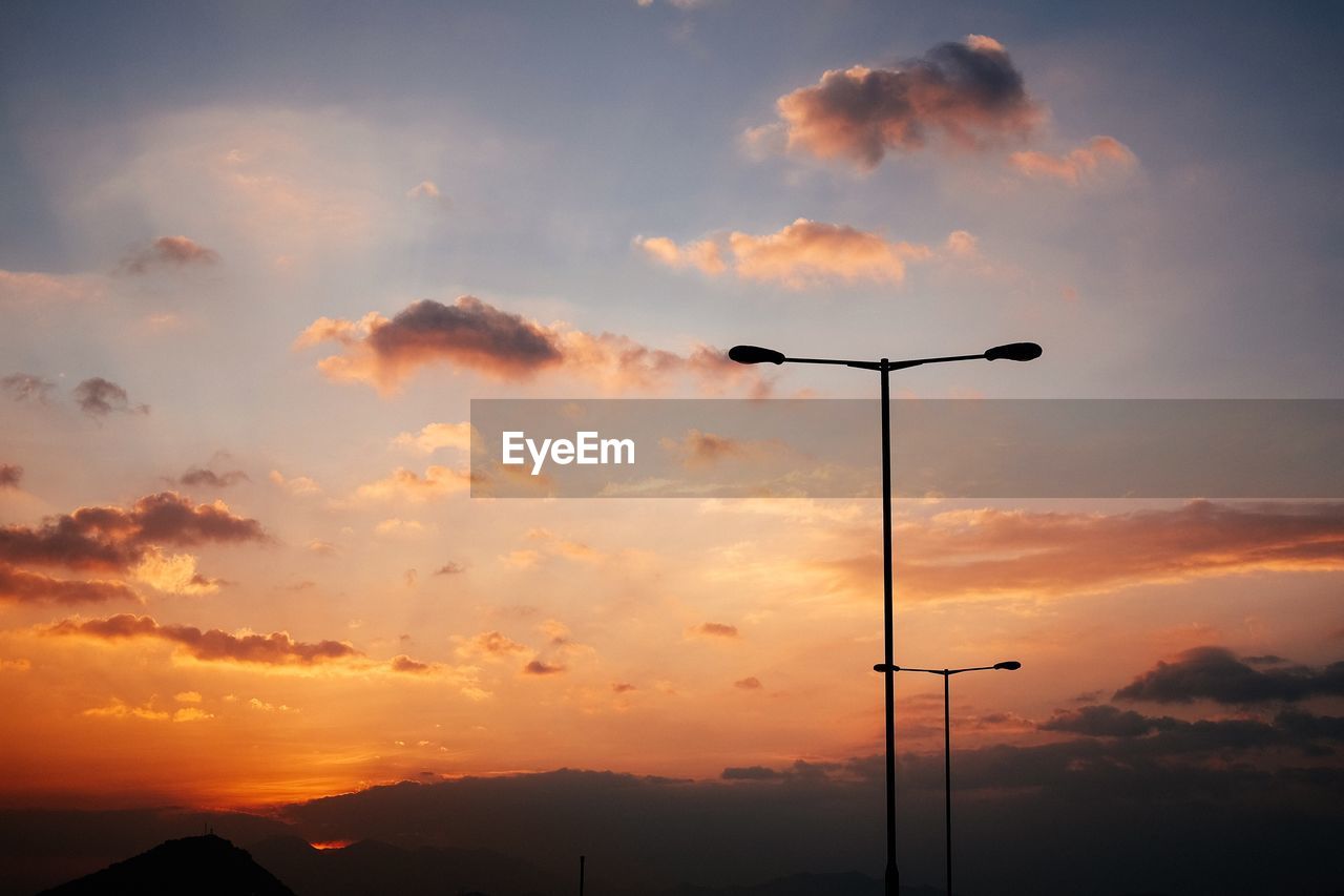 Silhouette street lights against sky during sunset