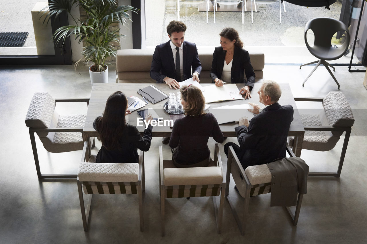 High angle view of financial advisors and customers discussing during meeting at law firm
