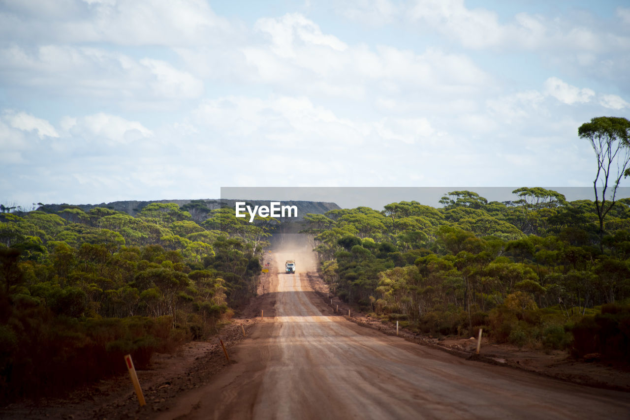 empty road amidst landscape against cloudy sky