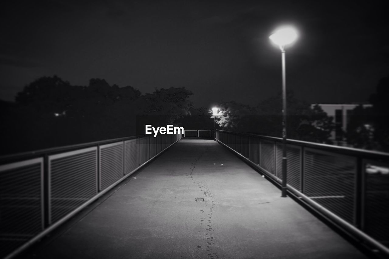 EMPTY FOOTPATH AMIDST ILLUMINATED STREET LIGHT IN CITY