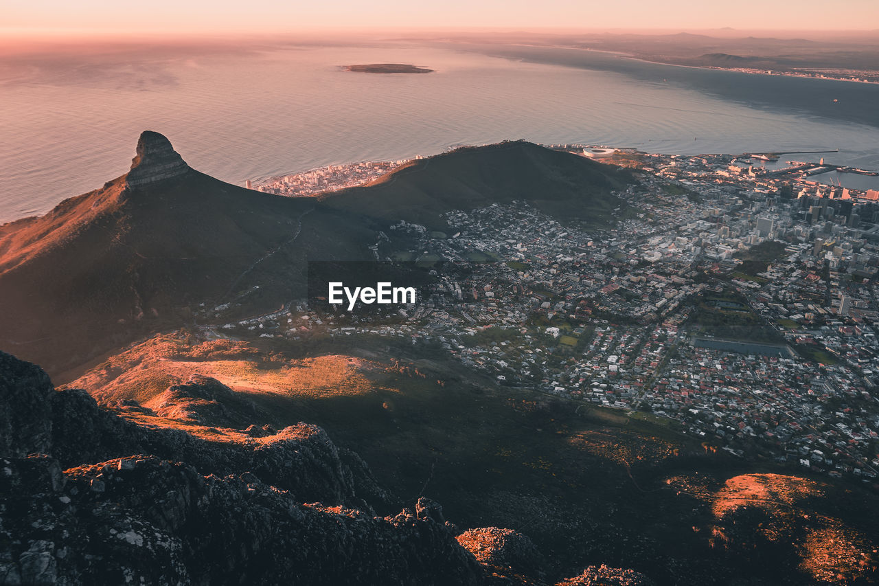 Aerial view of cityscape by sea at sunset